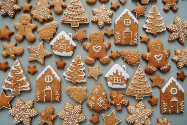 Ev şeklinde kurabiyeler, Noel ağacı, bir insan, kremayla süslenmiş bir yıldız. Kış tatili şablonu, zencefilli çörek seti, desenlerin düzeni..