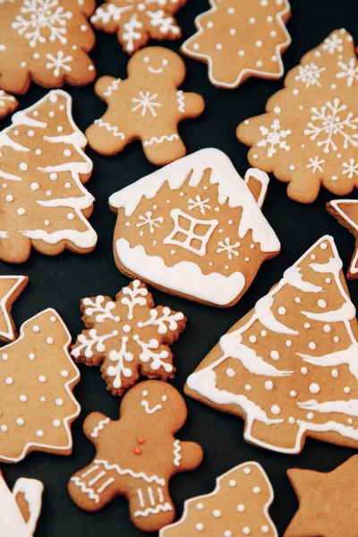 El patrón de vacaciones de invierno-un conjunto de pan de jengibre, el diseño del patrón sobre un fondo oscuro. galletas en forma de casa, un árbol de Navidad, una persona, una estrella decorada con hielo. — Foto de Stock