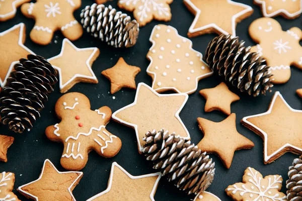 El patrón de vacaciones de invierno-un conjunto de pan de jengibre, el diseño del patrón sobre un fondo oscuro. galletas en forma de casa, un árbol de Navidad, una persona, una estrella decorada con hielo. — Foto de Stock