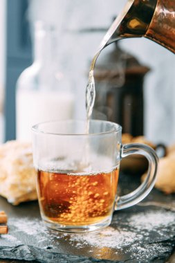 Ev ortamında buharlı bir çay akıntısı. Çay seremonisi. Çaya kaynar su dökülüyor..