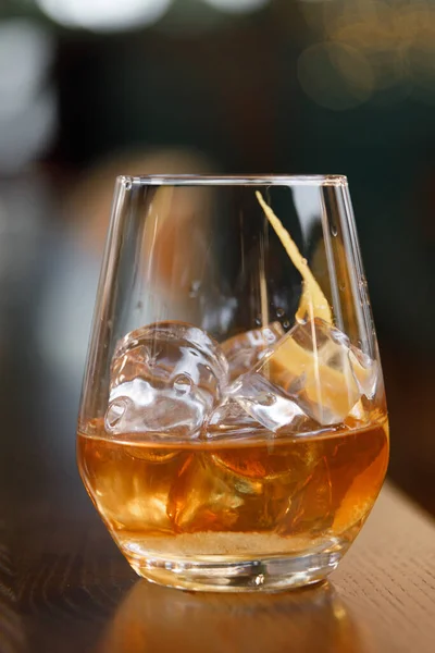 A glass of whiskey on the rocks on the bar. A glass of strong alcohol close - up in macro. — Stock Photo, Image