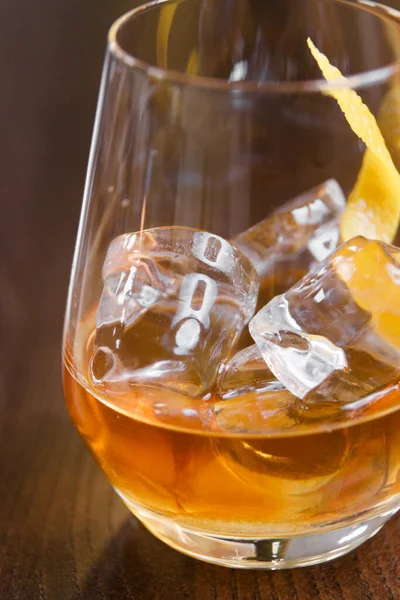 A glass of whiskey on the rocks on the bar. A glass of strong alcohol close - up in macro. — Stock Photo, Image