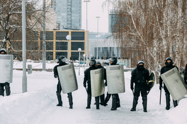 Yekaterinburg, Russia - January 23, 2021: Riot police run to disperse civilians. Military with weapons and shields in winter.