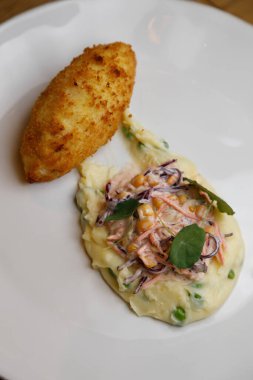 Beyaz tabakta ulusal bir yemek. Patates püresi, sebze ve mısırlı Kiev pirzolası..