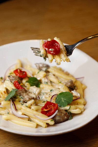 Restaurant dish close-up. Tagliatelle with mushrooms, parmesan and thyme and dried cherry tomatoes.