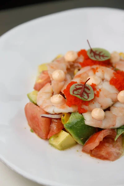 Shrimp salad close-up. Shrimp with tomato, avocado, pickled onion and flying fish roe.