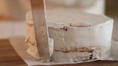 Kadın bir pasta şefi bisküvinin üzerine krema döker, hem de pasta poşeti ile, yakın çekim manzaralı. Bir pastane şefi ev yapımı Esterhazy keki hazırlar..