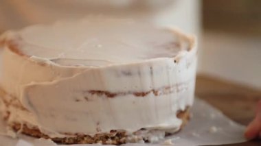 Kadın bir pasta şefi bisküvinin üzerine krema döker, hem de pasta poşeti ile, yakın çekim manzaralı. Bir pastane şefi ev yapımı Esterhazy keki hazırlar..