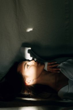 Yüzünde ve gözlerinde karanlık bir çerçeve içinde bir güneş ışığı. Uzanmış genç ve çekici bir kızın portresi..