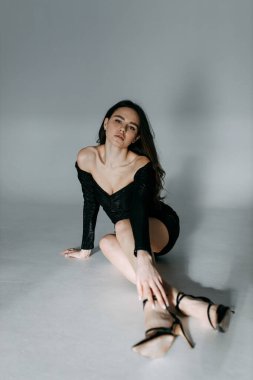 Beyaz siklonamada bir kızın model testleri. Siyah kısa elbiseli genç bir esmer poz verir ve yere yatar..