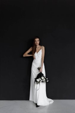 Zarif bir elbise içinde modern moda bir gelin. Siyah arka planda beyaz gelinlik içinde güzel bir kadın..