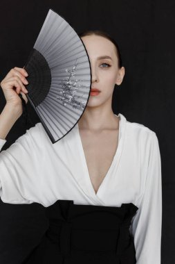 Stüdyoda modern bir geyşa stili. Siyah arka planda beyaz Asyalı takım elbiseli güzel bir kadın..