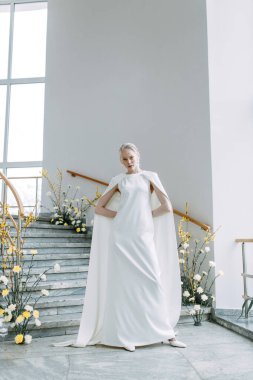 Sarı gözlüklü modern çiçekçiler. Gelinin modaya uygun görüntüsü. Beyaz elbiseli modaya uygun bir gelin, parlak bir iç mekanda, merdivenlerde..