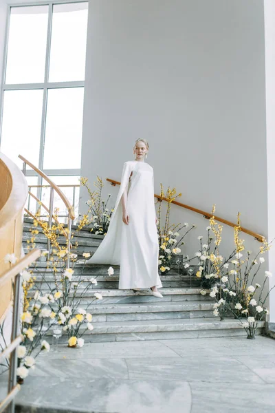 黄色阴影下的现代植物学 新娘的形象很时髦 一个穿着白色衣服的时髦新娘在明亮的内部楼梯上 — 图库照片