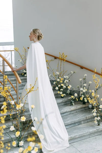 黄色阴影下的现代植物学 新娘的形象很时髦 一个穿着白色衣服的时髦新娘在明亮的内部楼梯上 — 图库照片
