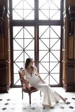 Gelinin koyu renkli, lakonik Avrupa tarzı bir görüntüsü. Beyaz elbiseli, şık, modern bir gelin. Keskin, kavramsal bir imaj..