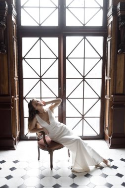 Gelinin koyu renkli, lakonik Avrupa tarzı bir görüntüsü. Beyaz elbiseli, şık, modern bir gelin. Keskin, kavramsal bir imaj..