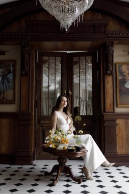 Gelinin koyu renkli, lakonik Avrupa tarzı bir görüntüsü. Beyaz elbiseli, şık, modern bir gelin. Keskin, kavramsal bir imaj..