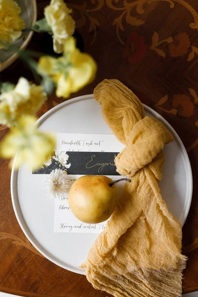 Wedding decor in trendy shades, composition on the table with printing. A delicate composition with yellow flowers and fruits, with wedding invitations.