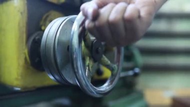 Küçük torna tezgahındaki ayarlanabilir direksiyonun elle kumandası. Bir işçi torna tezgahı kurar, yakın plan..