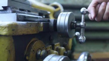 Küçük torna tezgahındaki ayarlanabilir direksiyonun elle kumandası. Bir işçi torna tezgahı kurar, yakın plan..