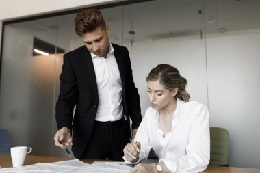 Bir erkek ve bir kadın iş konularını tartışıyor. Bir çift dizüstü bilgisayar başında çalışıyor ve ofis planlarında gülümsüyor..
