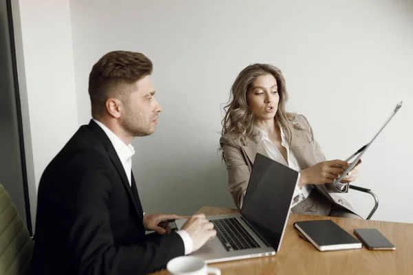 A man and a woman discuss business matters. A couple working at a laptop and blueprints in their home office smile.