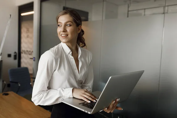 Girl close-up at work. Portrait of a businesswoman with a laptop writing on a document in her office.