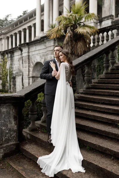 Hochzeit in einer alten Villa, ein glückliches Paar Händchen haltend. Hochzeitszeremonie im europäischen Stil auf der Treppe. — Stockfoto
