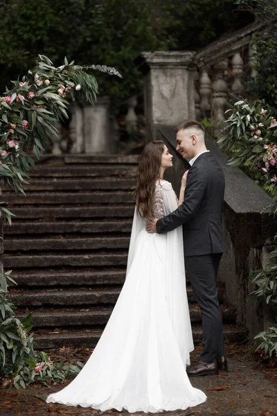 A wedding in an old villa, a happy couple of newlyweds. Round wedding arch, decorated with white flowers and greenery, in front of the old Italian architecture.