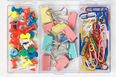 Ofis için ataç ve düğme dolu bir kutu. Plastik ve kauçuk karışımıyla kaplı renkli ataçların üst görünümü.