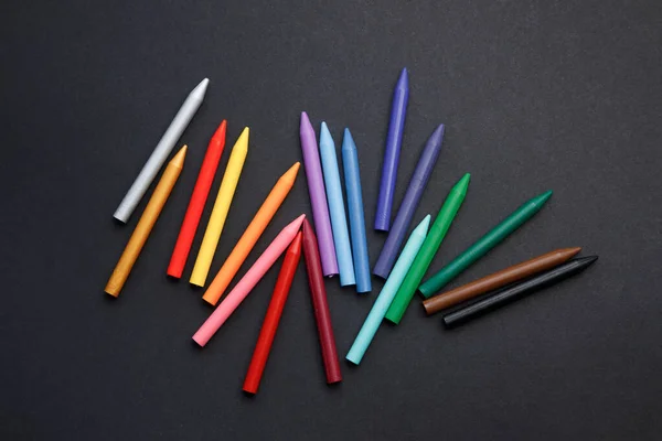 Een set kleurrijke krijtjes in de vorm van een regenboog op tafel. Kinderen school potloden op een donkere achtergrond. — Stockfoto