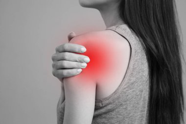 Omuz ve eklem yaralanmaları ve iş yerinde yorgunluk. Yaralanma bölgesi, boş bir arkaplandaki görüntü. Kızın omzunda bir spazm..