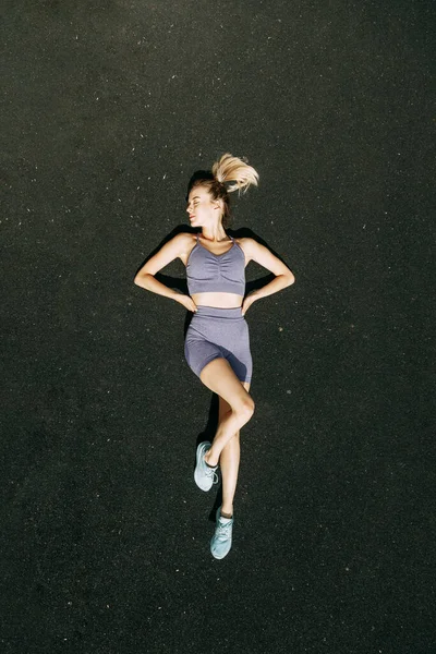 Uma mulher esportiva treina e faz exercícios em um estádio de fitness. Aquecimento ao ar livre, alongamento . — Fotografia de Stock