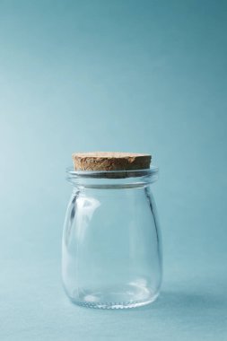 Kozmetik ya da su için bir kavanoz, metin için bir yer. Mavi arka planda cam bir kavanoz..