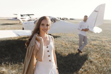 Gülümseyen insanlar ve arkada özel bir uçak. Bir çift aşık, kokpitte kendi uçaklarında..