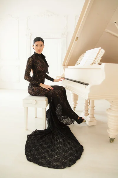 Girl in dress at the piano. — Stock Photo, Image