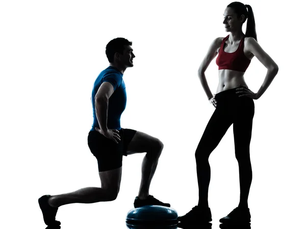 Entrenador hombre mujer ejercitando sentadillas en bosu silueta —  Fotos de Stock