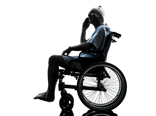 Homem ferido no telefone feliz em silhueta de cadeira de rodas — Fotografia de Stock