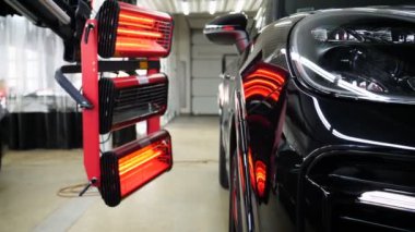 Vücut parçalarının kızılötesi kuruması macun sürdükten sonra ve çalışma ortamında çalışan kırmızı fenerlerle tamirhanedeki beyaz bir off-road aracına boya sürdükten sonra. Araba Seramik, Yavaş Hareket kavramı.
