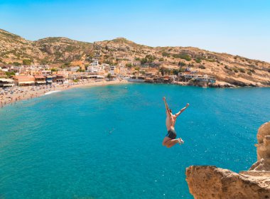 Genç adam uçurumun denizin üzerinden atlama.