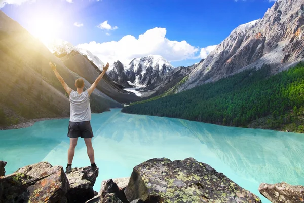 美しい山間の湖近くの上げられた手で立っているハイカー — ストック写真