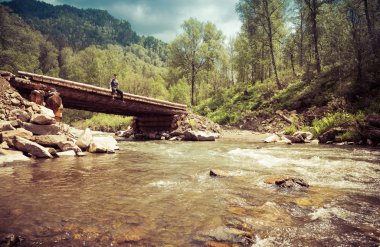 Adam bir ahşap köprü üzerinde oturur