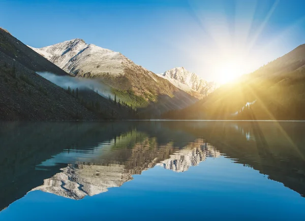 Nascer do sol e montanhas refletidas na água — Fotografia de Stock