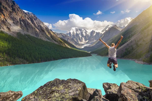 Bela paisagem montanhosa com lago e homem pulando — Fotografia de Stock