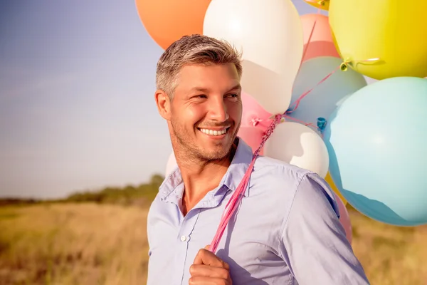 Globos que sostienen al hombre al aire libre —  Fotos de Stock