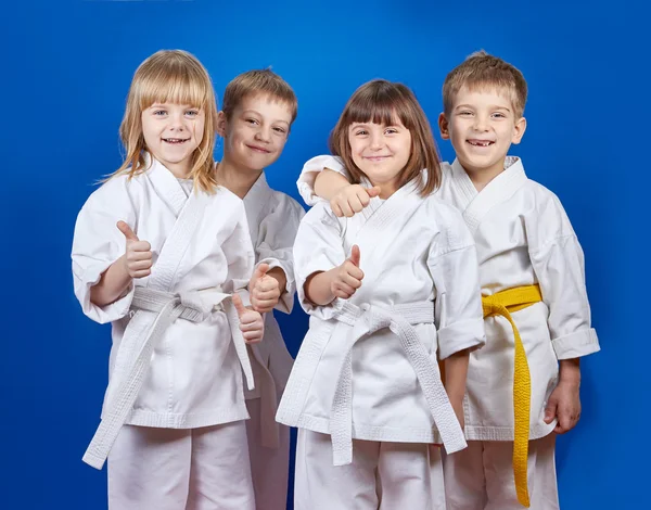 Four cheerful sportsman in karategi are showing finger super — Stock Photo, Image