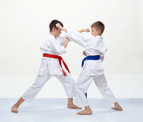 På en vit bakgrund tränar idrottare block och sparkar i karate — Stockfoto