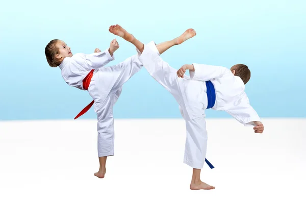 Boy and girl hit a kick on a light background — Stock Photo, Image