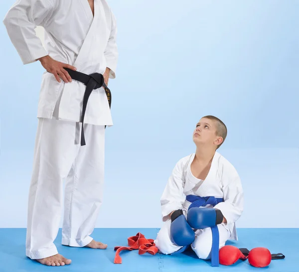 Athlete sitting on a mat listening to the instruction of coach — Stock Photo, Image